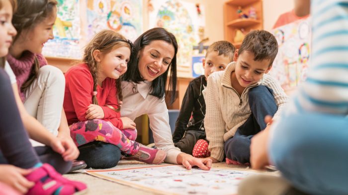 Preschool,Teacher,Talking,To,Group,Of,Children,Sitting,On,A Preschool,Teacher,Talking,To,Group,Of,Children,Sitting,On,A