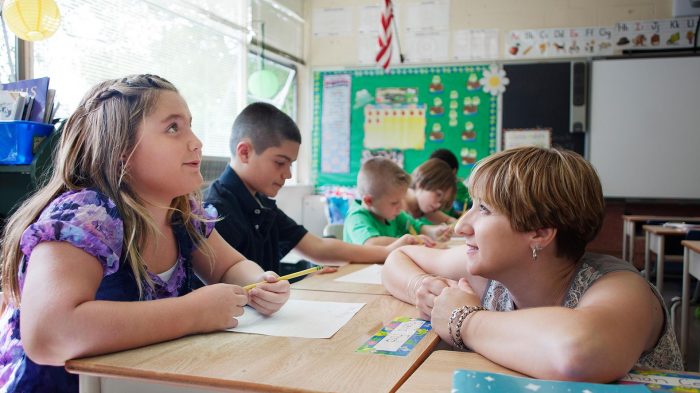 Child care worker helps children sound out words in book